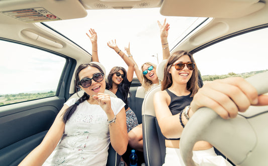 Group of friends enjoying a fun road trip and singing together in a car.